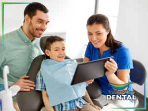 Family dentist treating young patient while parent watches